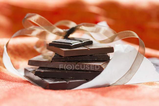 Stack of chocolates on paper with ribbon — Stock Photo