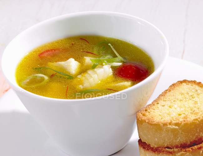 Vista de perto da sopa de açafrão com peixe, alho-poró e tomate — Fotografia de Stock