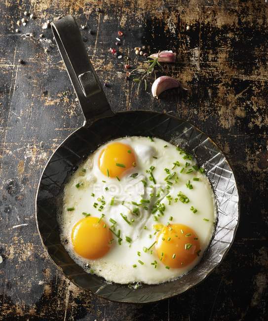 Fried eggs with chives in frying pan — Stock Photo