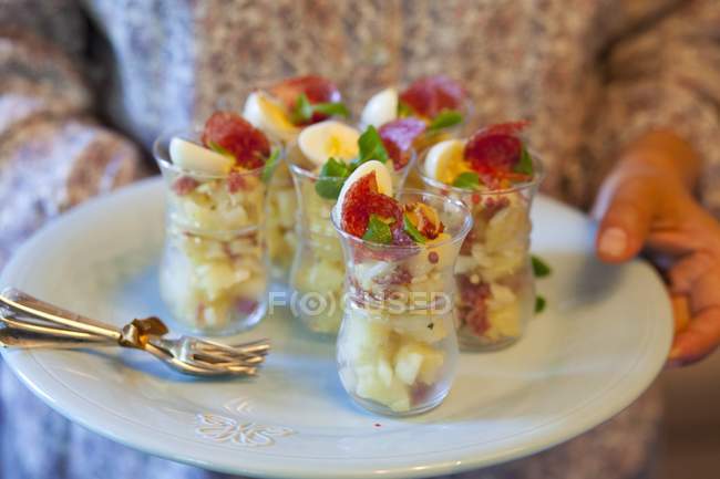 Pessoa segurando saladas de batata com salame — Fotografia de Stock