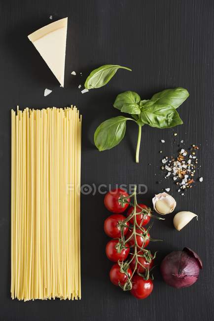 Ingredientes para espaguete com tomates na superfície preta — Fotografia de Stock