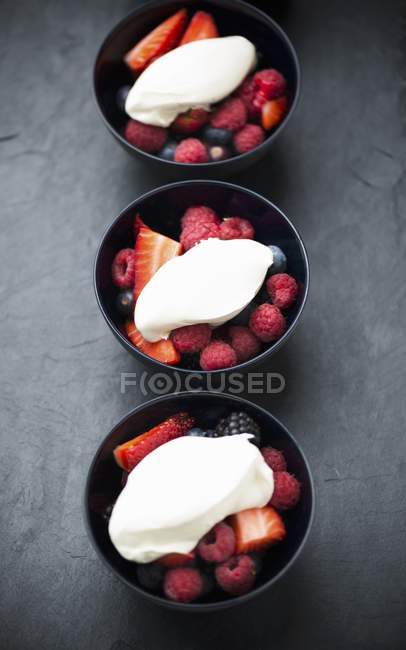 Closeup view of fresh berries with cream in bowls — Stock Photo
