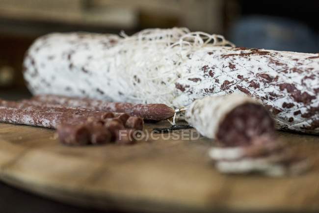 Sliced hard sausage on wooden plate — Stock Photo