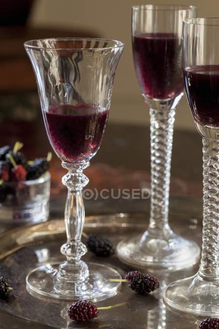 Primo piano vista del liquore di gelso in tre bicchieri a stelo su un vassoio — Foto stock