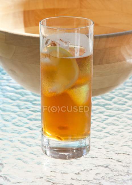 Closeup view of fruit iced drink with lemon and wooden bowl — Stock Photo