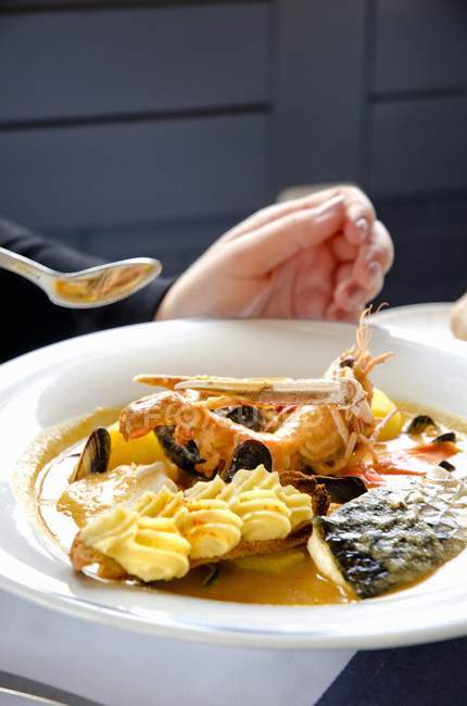 Nahaufnahme einer Person, die Bouillabaisse mit Fisch und Garnelen isst — Stockfoto
