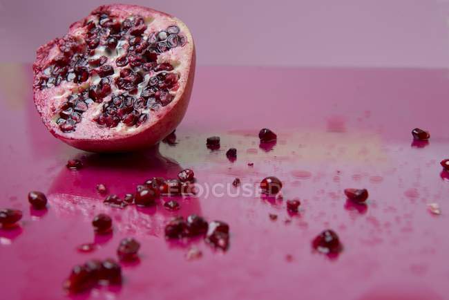 Pomegranate with seeds strewn — Stock Photo