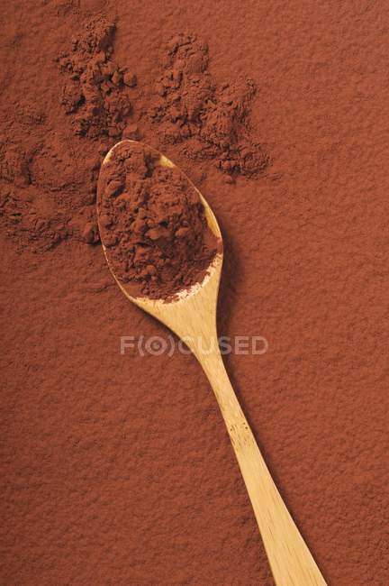 Primo piano vista dall'alto del cacao in polvere su cucchiaio di legno e superficie marrone — Foto stock