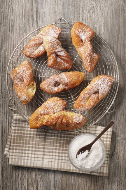 Top view of fried dough sweets with powdered icing sugar on wire cooling rack — Stock Photo