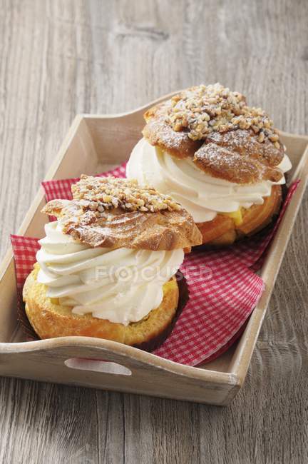 Closeup view of cream puff pastries with tissues in wooden tray — Stock Photo