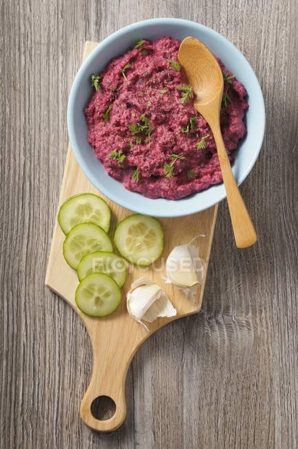 Beetroot hummus in blue bowl with wooden spoon over desk — Stock Photo