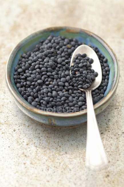 Closeup view of black Beluga lentils with spoon in bowl — Stock Photo