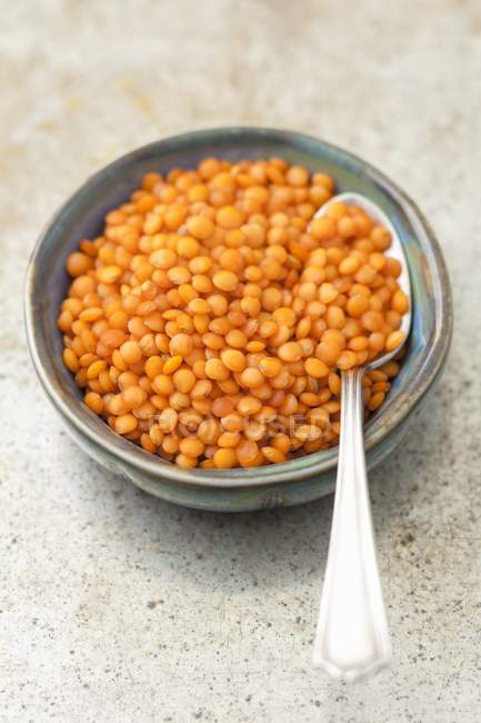 Closeup elevated view of red lentils and spoon in bowl — Stock Photo