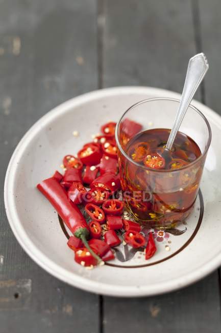 Chilli rings in oil  on white plate with glass — Stock Photo
