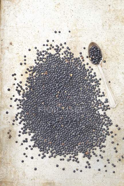 Vue de dessus des lentilles noires de béluga avec une cuillère sur une surface grise — Photo de stock