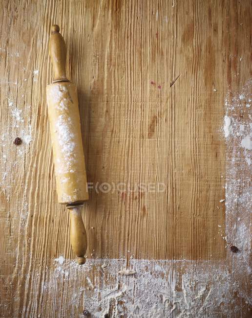 Vista superior de uma superfície de madeira enfarinhada e um rolo — Fotografia de Stock