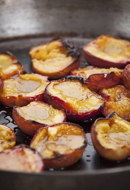 Closeup view of fried nectarines halves in a pan — Stock Photo