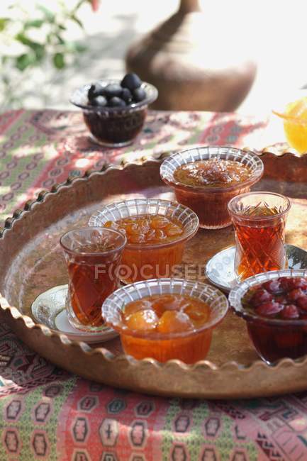 Стаканы чая и конфеты консерванты фрукты на столе снаружи — стоковое фото