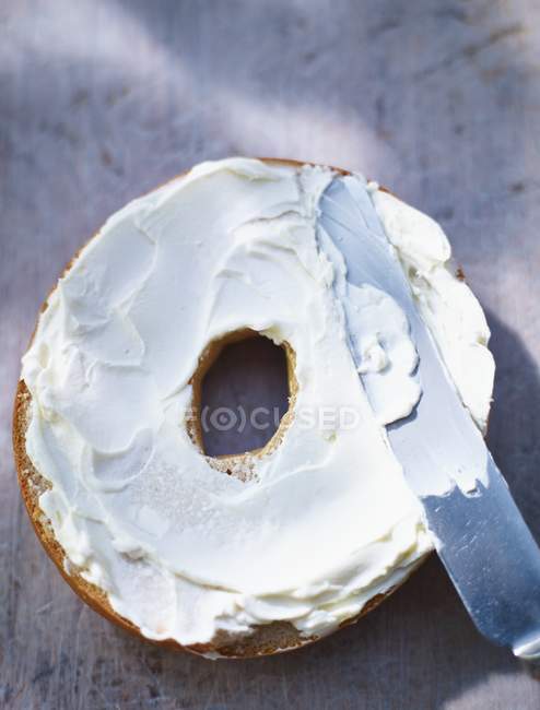 Metade de bagel espalhado com creme — Fotografia de Stock