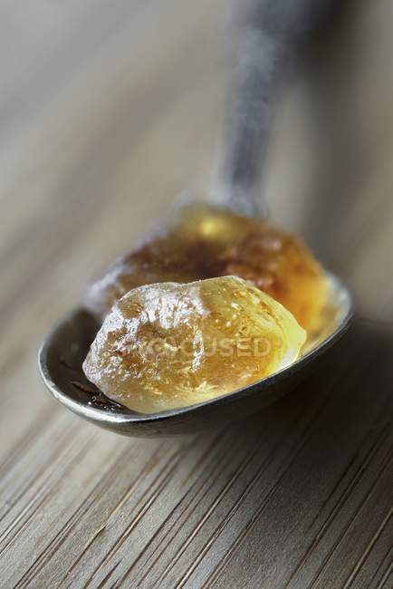 Vista close-up de açúcar de rocha marrom em uma colher de prata — Fotografia de Stock