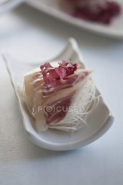 Bream sashimi on strips of radish over white surface — Stock Photo