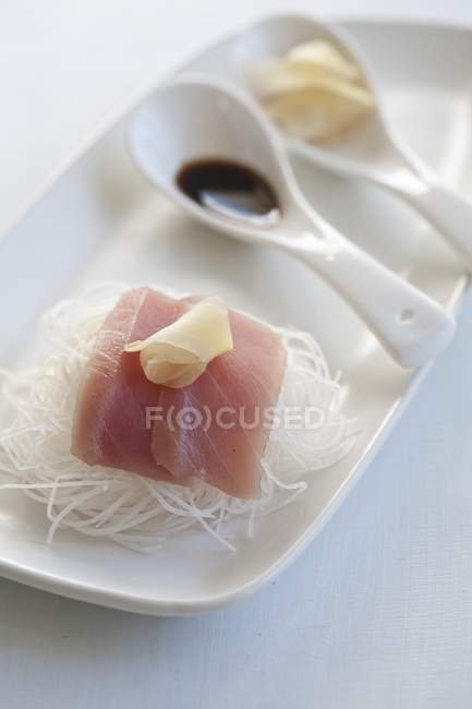 Сашими из тунца с имбирем на белой тарелке с ложками — стоковое фото