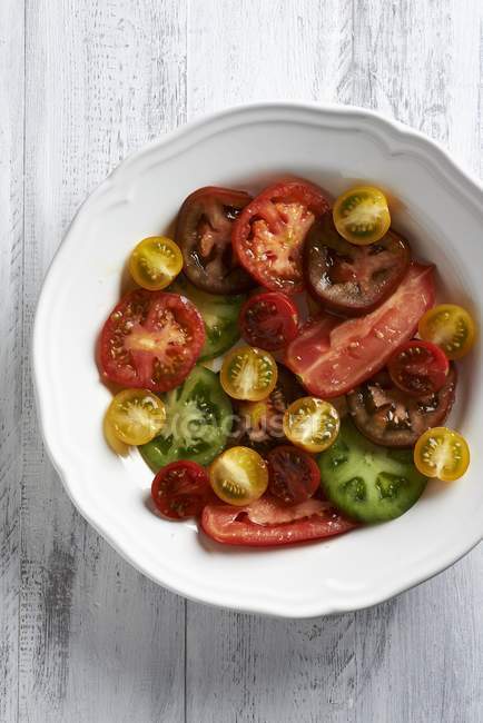 Verschieden farbige Tomatenscheiben auf einem weißen Teller — Stockfoto