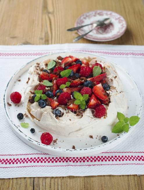 Closeup view of Pavlova with berries and mint leaves on platter — Stock Photo