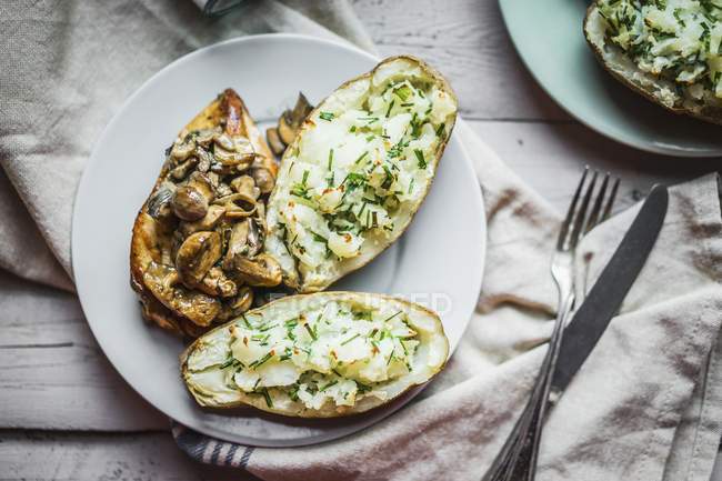 Grilled chicken with mushrooms and baked potatoes on white plate over towel — Stock Photo