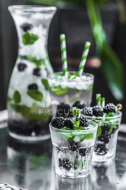 Closeup view of water with blackberries, ice cubes and mint — Stock Photo