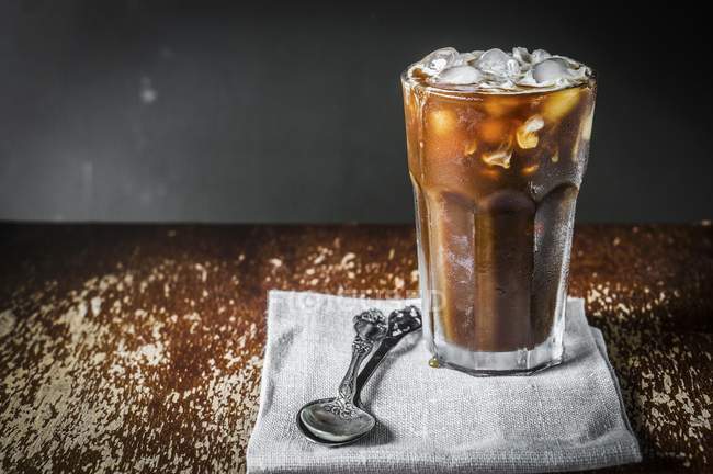 Closeup view of iced coffee in glass with spoons on cloth — Stock Photo