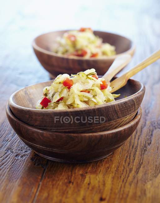 Courgette coleslaw with diced peppers in wooden bowls over wooden surface — Stock Photo
