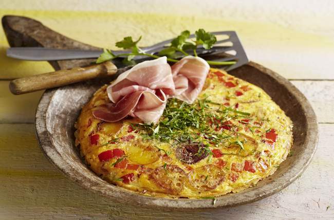 Catalan tortilla with peppers and Serrano ham on brown plate on wooden surface — Stock Photo