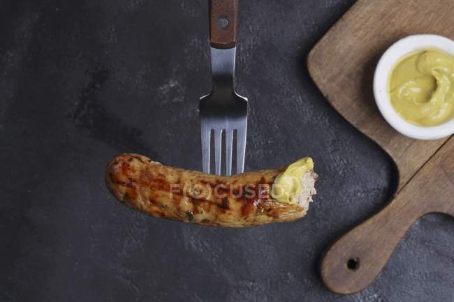Sausage with mustard on fork — Stock Photo