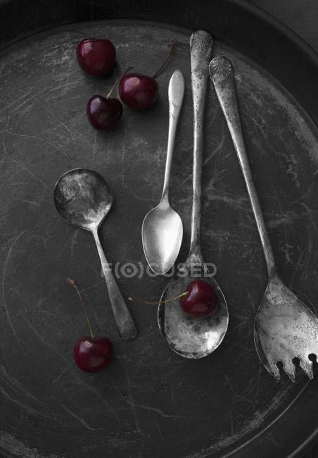 Old silver spoons and cherries — Stock Photo