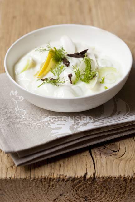 Цацики с огурцом, лимонами и укропом на белой тарелке поверх полотенца — стоковое фото