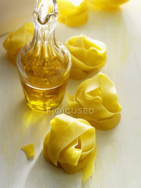 Pappardelle pasta nests and olive oil — Stock Photo