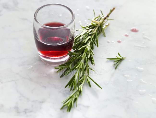 Glas Rotwein und ein Zweig Rosmarin — Stockfoto
