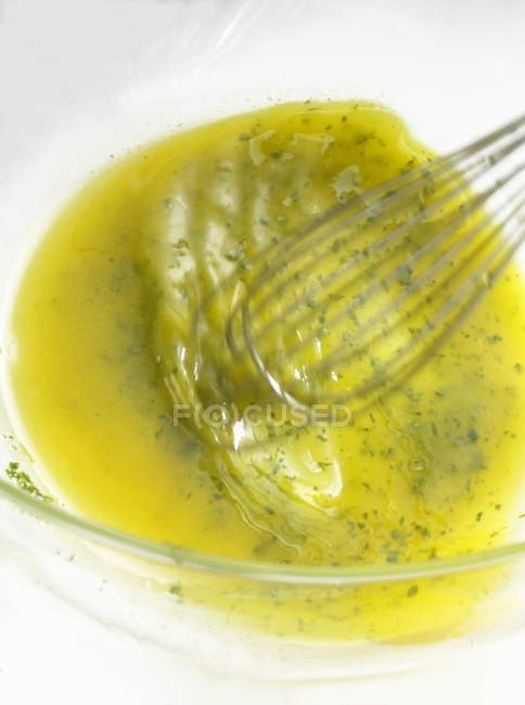 Vue rapprochée du mélange de vinaigrette dans un bol avec un fouet — Photo de stock