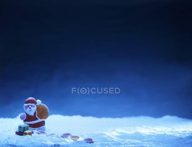 Vista de primer plano de Papá Noel con dulces contra una superficie azul - foto de stock