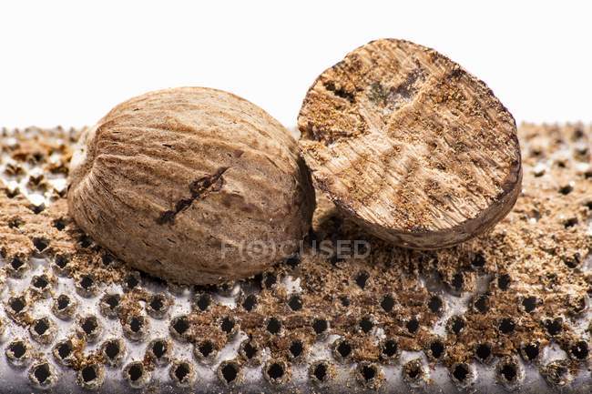 Nutmegs crudos en rallador - foto de stock