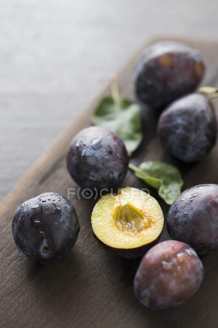 Damsons with half on wooden board — Stock Photo