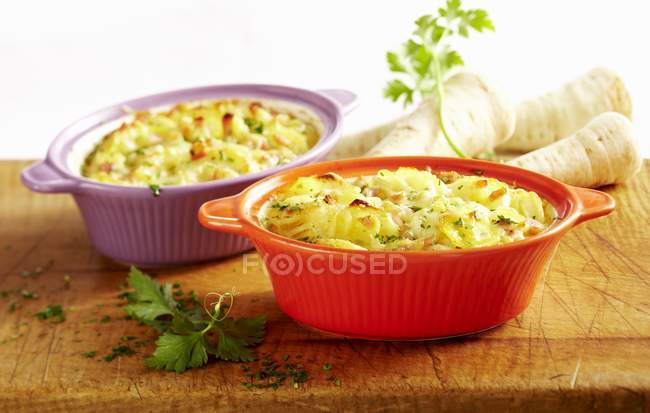 Gratin with Hamburg parsley, potatoes and ham in colored dished — Stock Photo