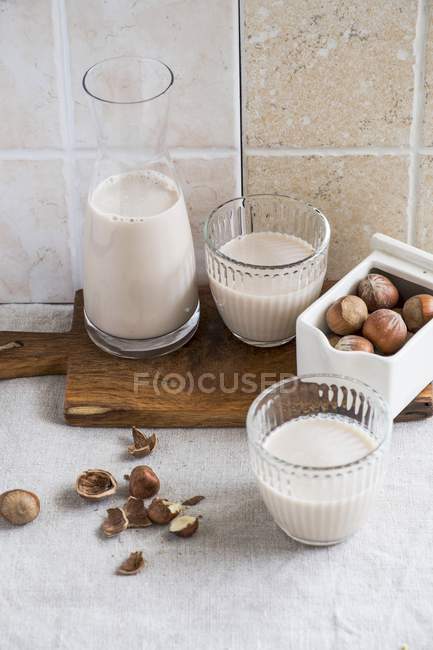Milk and hazelnuts in glasses — Stock Photo