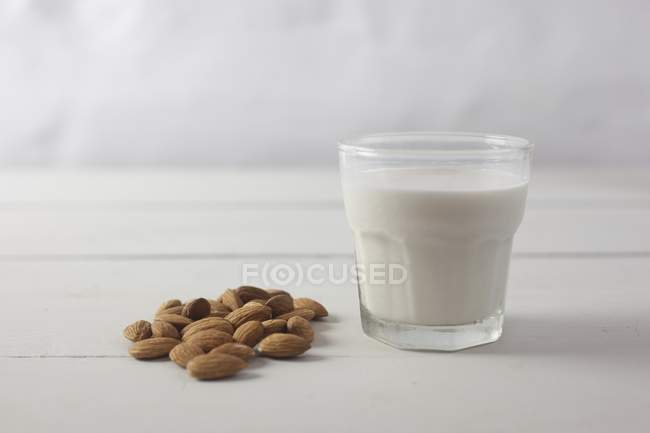 Almendras y un vaso de leche - foto de stock