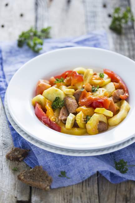 Hungarian lesco with vegetables and sausage on white plate over towel — Stock Photo
