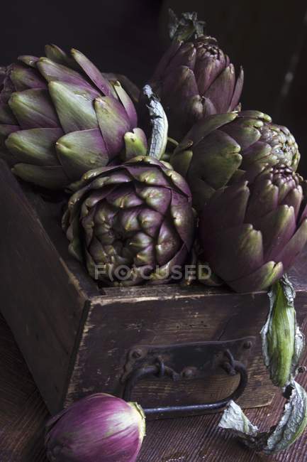 Alcachofas en cajón de madera - foto de stock