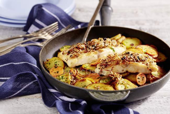 Spiced catfish with fried potatoes on pan over towel — Stock Photo
