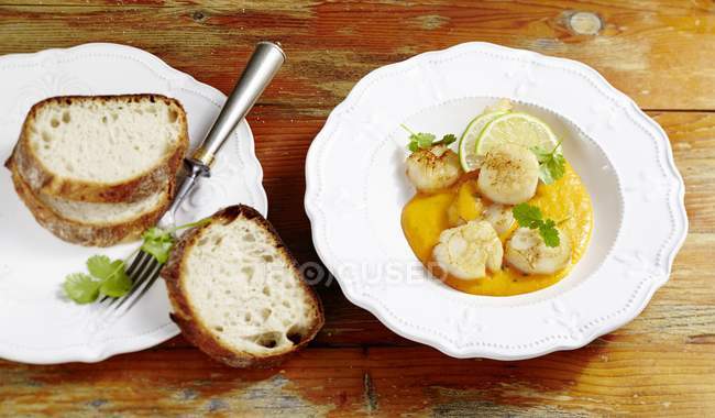 Elevated view of scallops in salsa sauce with lime slices and bread — Stock Photo