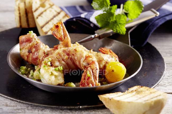 Vista de cerca de langostinos envueltos en tocino con hierbas - foto de stock